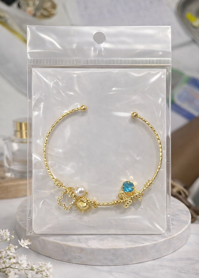 Gold Charm Open Cuff Bracelet – Sun, Pearl & Blue Crystal Design